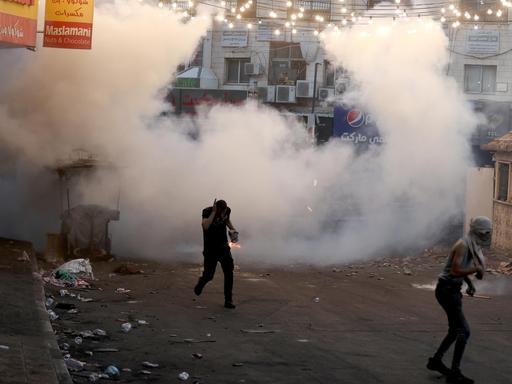 In Dschenin im Westjordanland läuft ein Palästinenser vor einer Tränengaswolke der israelischen Armee davon. 
