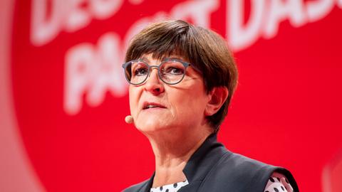 Saskia Esken spricht vor einer roten Wand.
