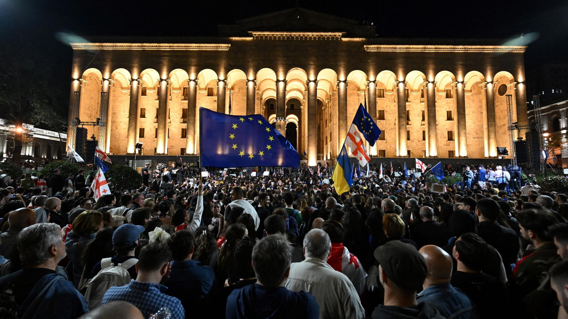 Demonstranten schwenken georgische National- und Europafahnen vor dem Parlamentsgebäude in Tiflis.