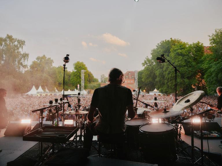 Der Schlagzeuger der Band "Element of Crime" ist von hinten auf einer Bühne zu sehen. Der Schlagzeuger der Band "Element of Crime" ist von hinten auf einer Bühne zu sehen.
