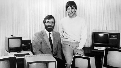 Die beiden Microsoft-Gründer Bill Gates (r) und Paul Allen (l) umgeben von vielen altmodischen Computern, aufgenommen im Jahr 1981. Das Bild ist schwarz-weiß. 
