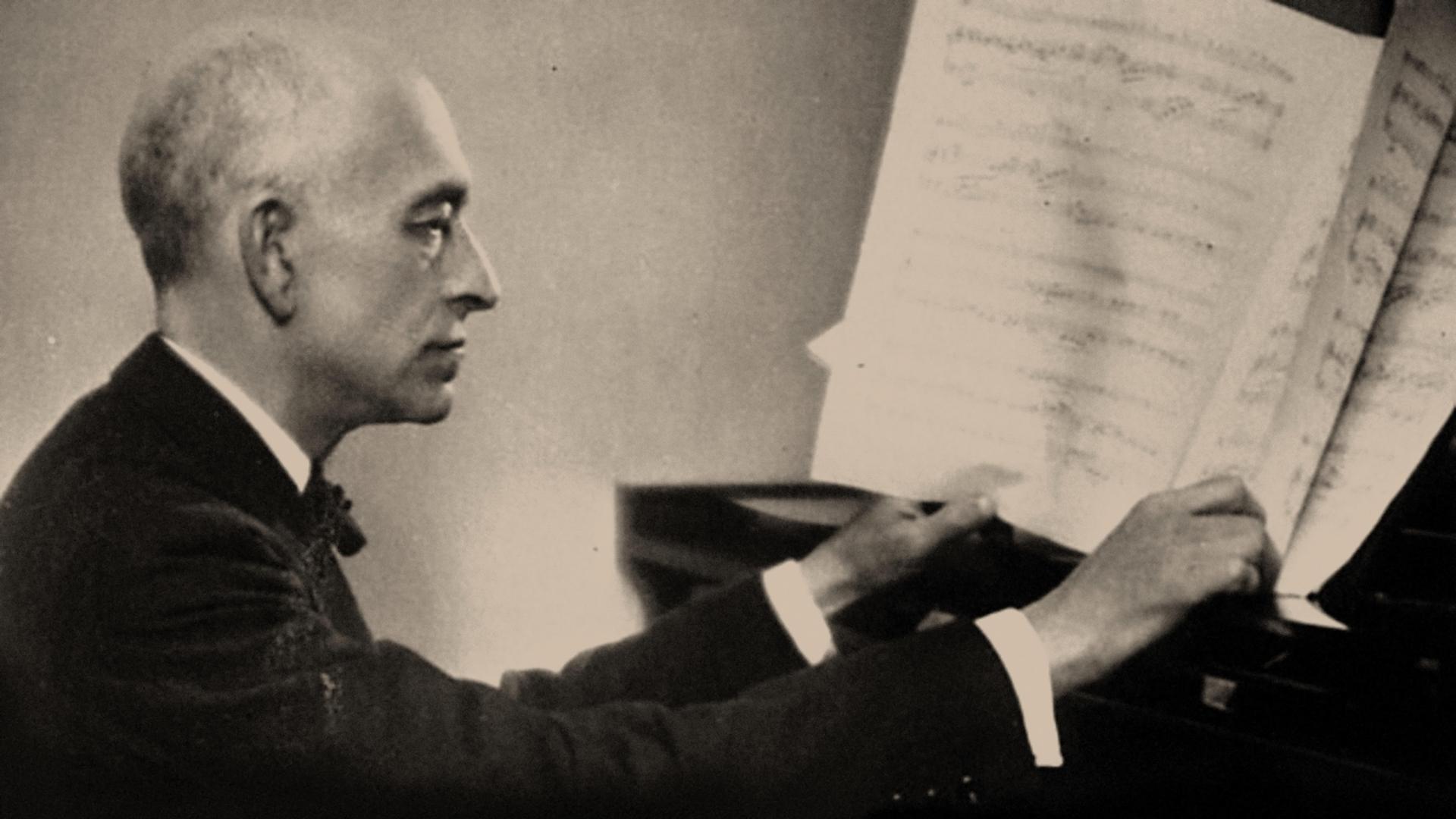 Der spanische Komponisten Manuel de Falla (1876-1946) sitzt am Klavier und blättert in einer Partitur. 
