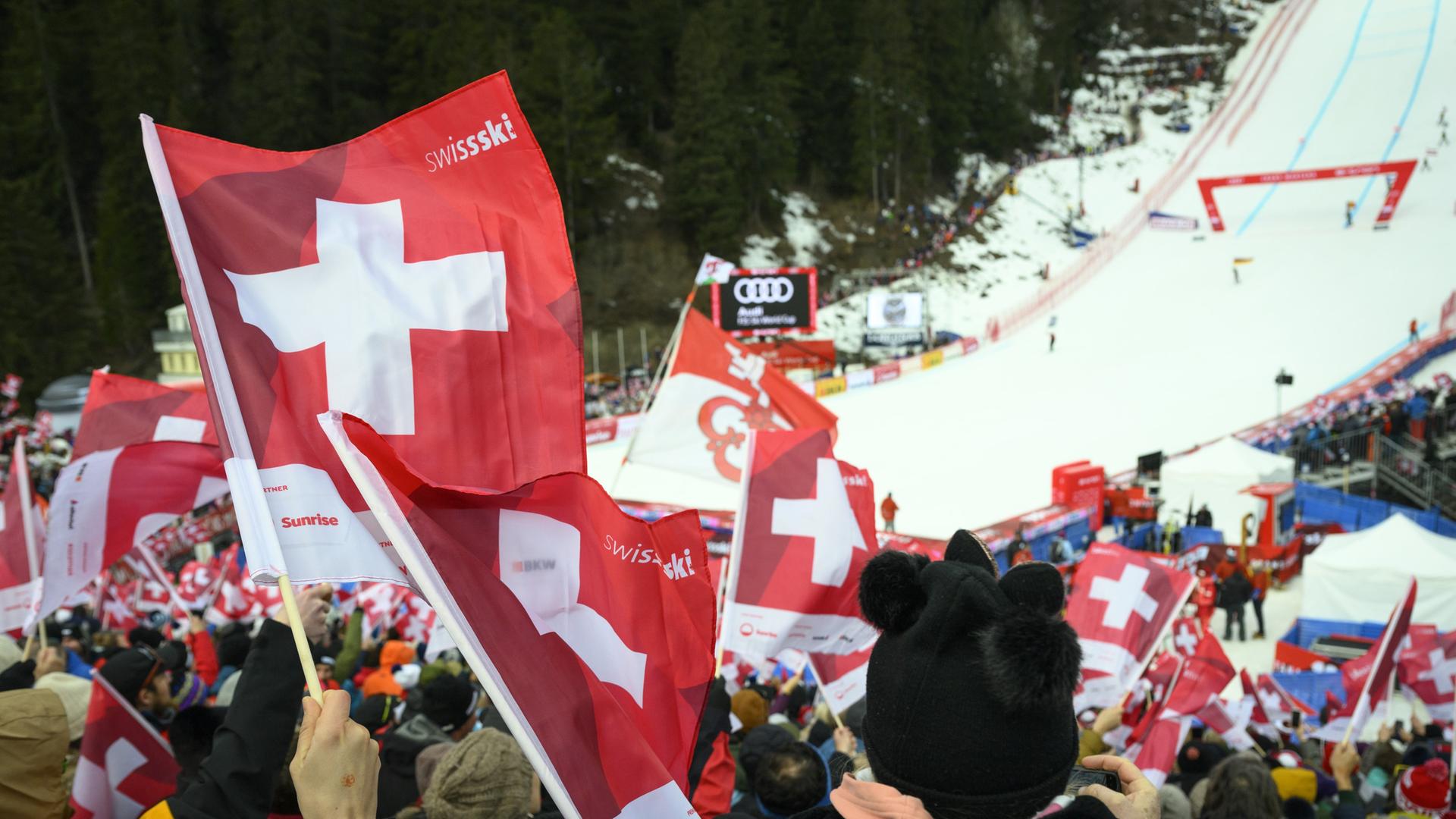 Fans der Schweizer Skifahrerinnen und -fahrer schwenken Fahnen im Abfahrts-Zieleinlauf von Crans-Montana.