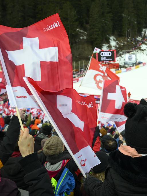 Fans der Schweizer Skifahrerinnen und -fahrer schwenken Fahnen im Abfahrts-Zieleinlauf von Crans-Montana.