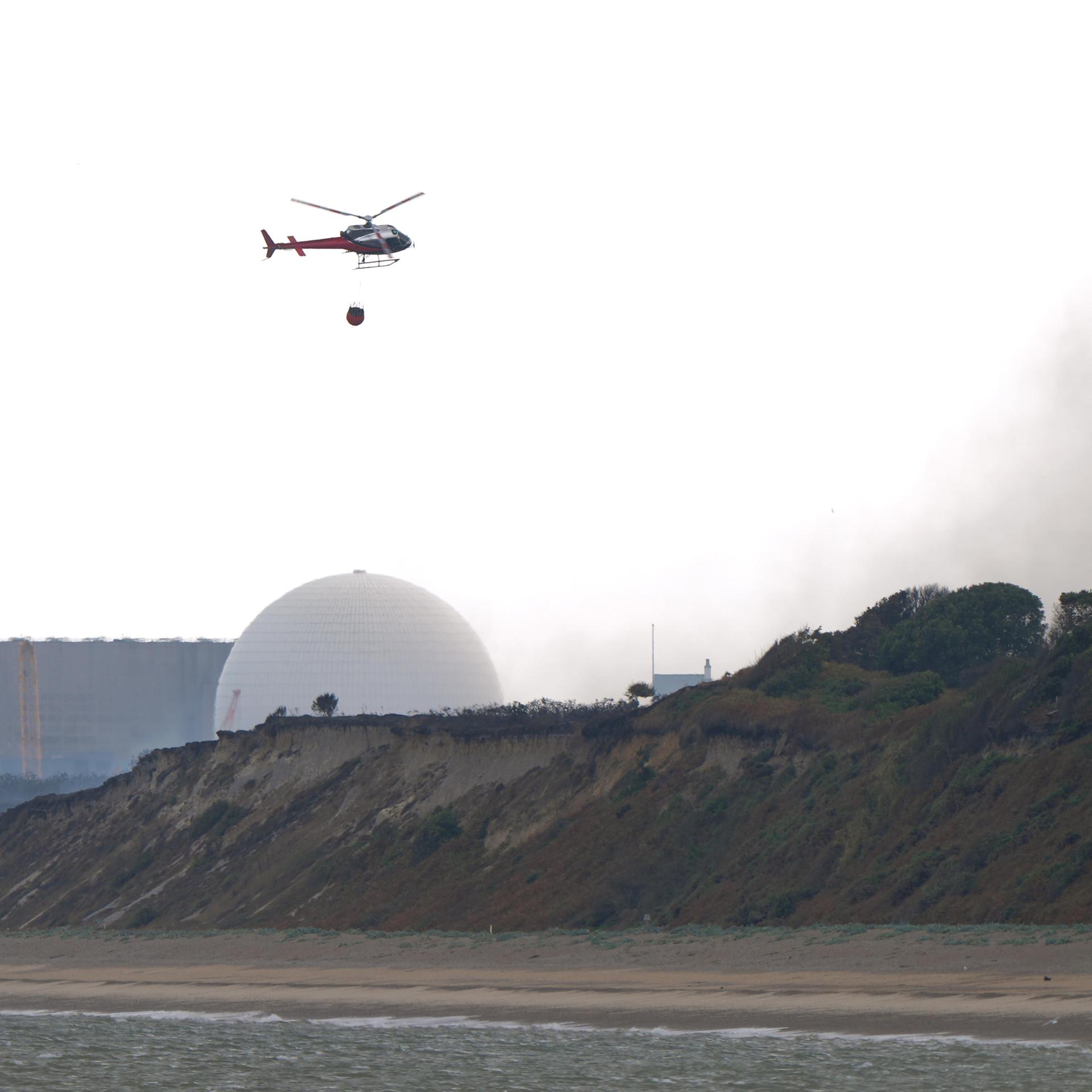 Ein Lösch-Helikopter fliegt über das Gebiet des Kernkraftwerks in der Nähe von Suffolk.