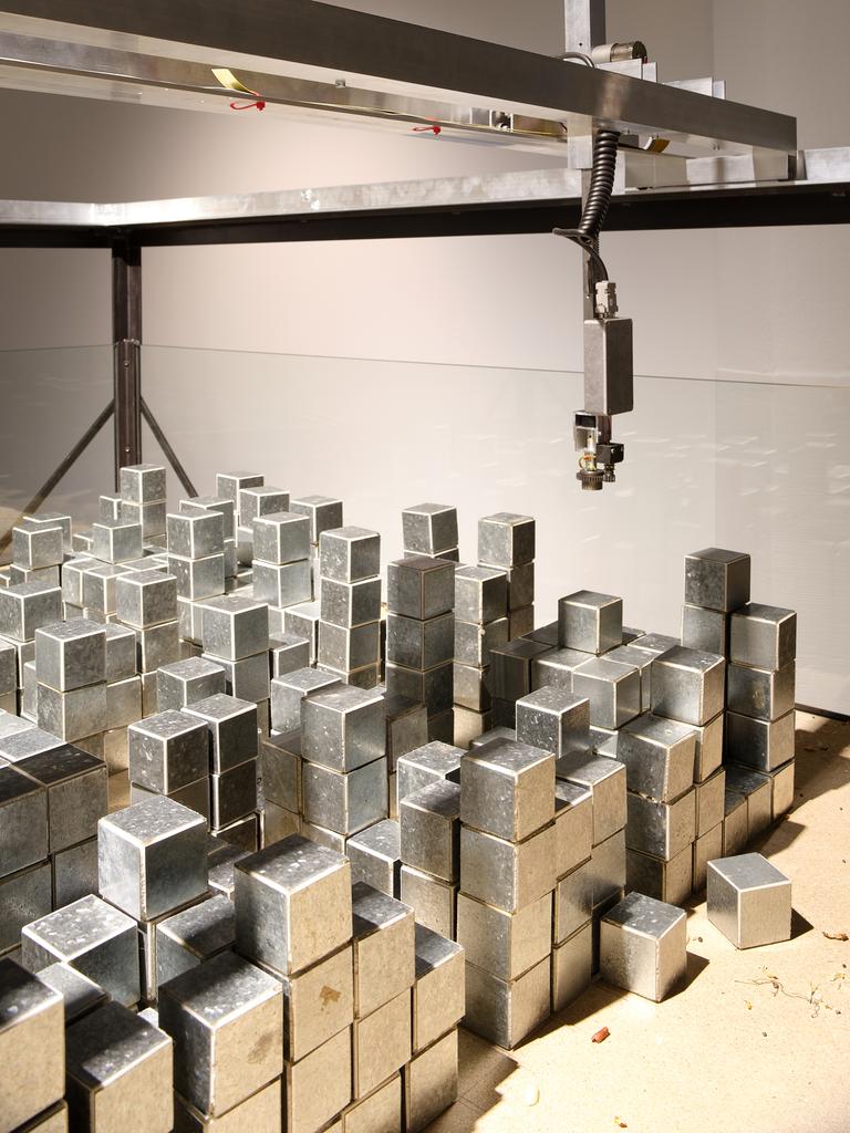 Ein Robotergreifarm schwebt über Metallwürfeln.