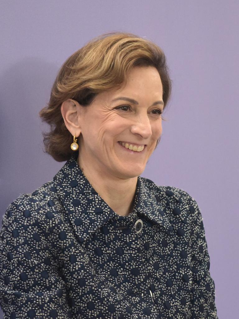 Anne Applebaum trägt eine gemusterte Bluse, steht vor einem violetten Hintergrund und schaut an der Kamera vorbei