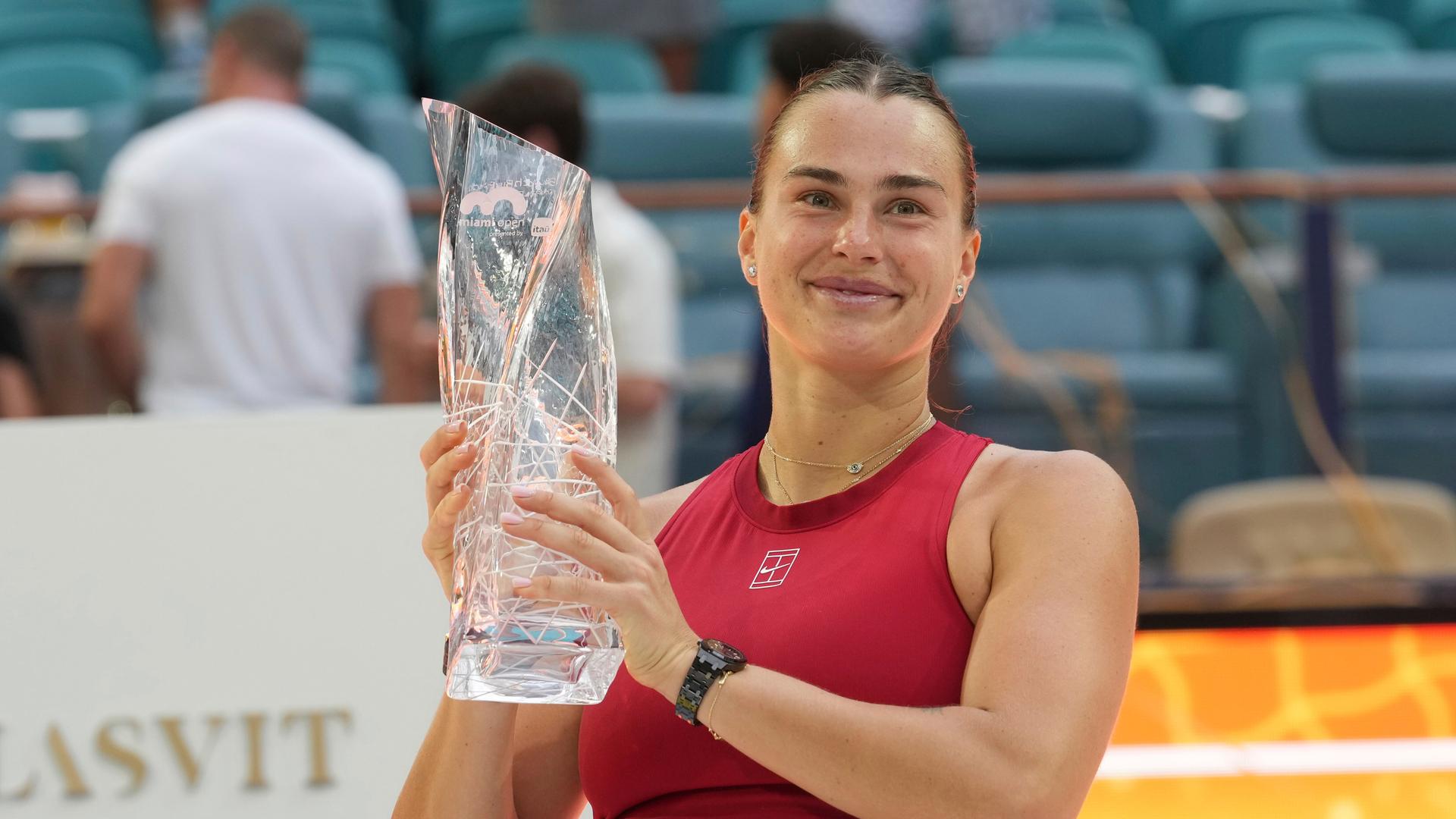 Tennisspielerin Aryna Sabalenka hält die Trophäe nach ihrem Sieg beim WTA-Turnier in Miami in den Händen und lächelt. Tennisspielerin Aryna Sabalenka hält die Trophäe nach ihrem Sieg beim WTA-Turnier in Miami in den Händen und lächelt.