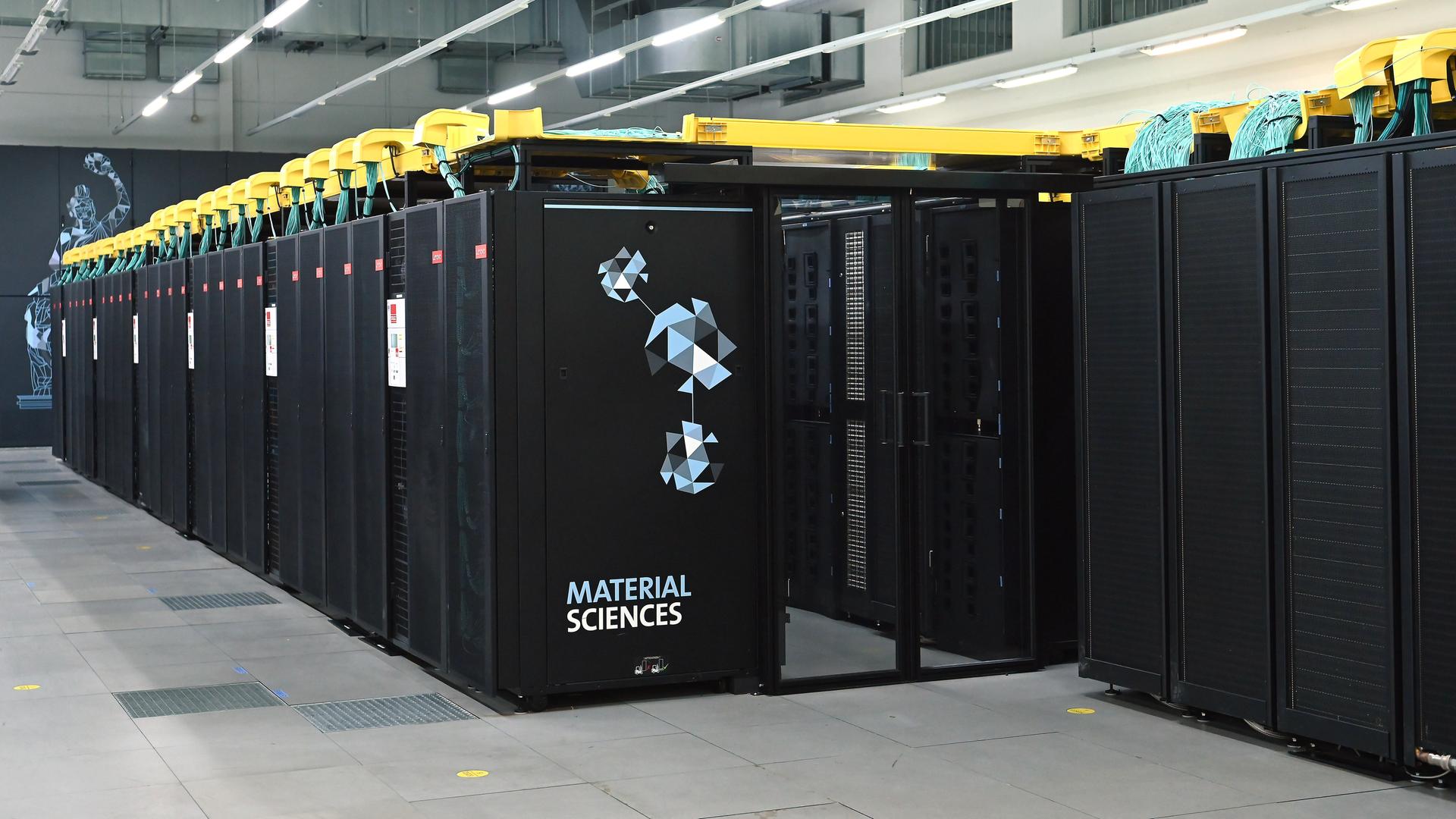 In einer Halle stehen viele schwarze Rechner nebeneinander. 