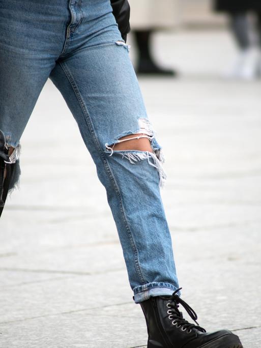 Zwei junge Frauen mit Handtasche und löchriger Jeans gehen über einen Platz. Zwei junge Frauen mit Handtasche und löchriger Jeans gehen über einen Platz.