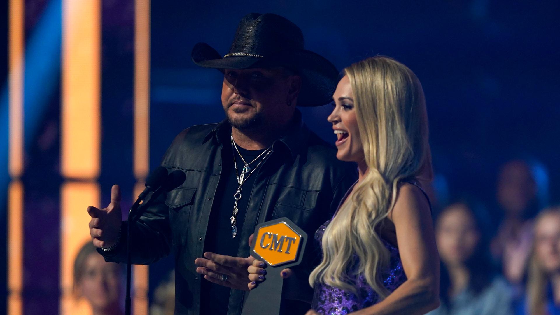 Eine blonde Frau hält eine Trophäe in der Hand auf der "CMT" steht, neben ihr steht ein Mann mit Cowboyhut. Eine blonde Frau hält eine Trophäe in der Hand auf der "CMT" steht, neben ihr steht ein Mann mit Cowboyhut.