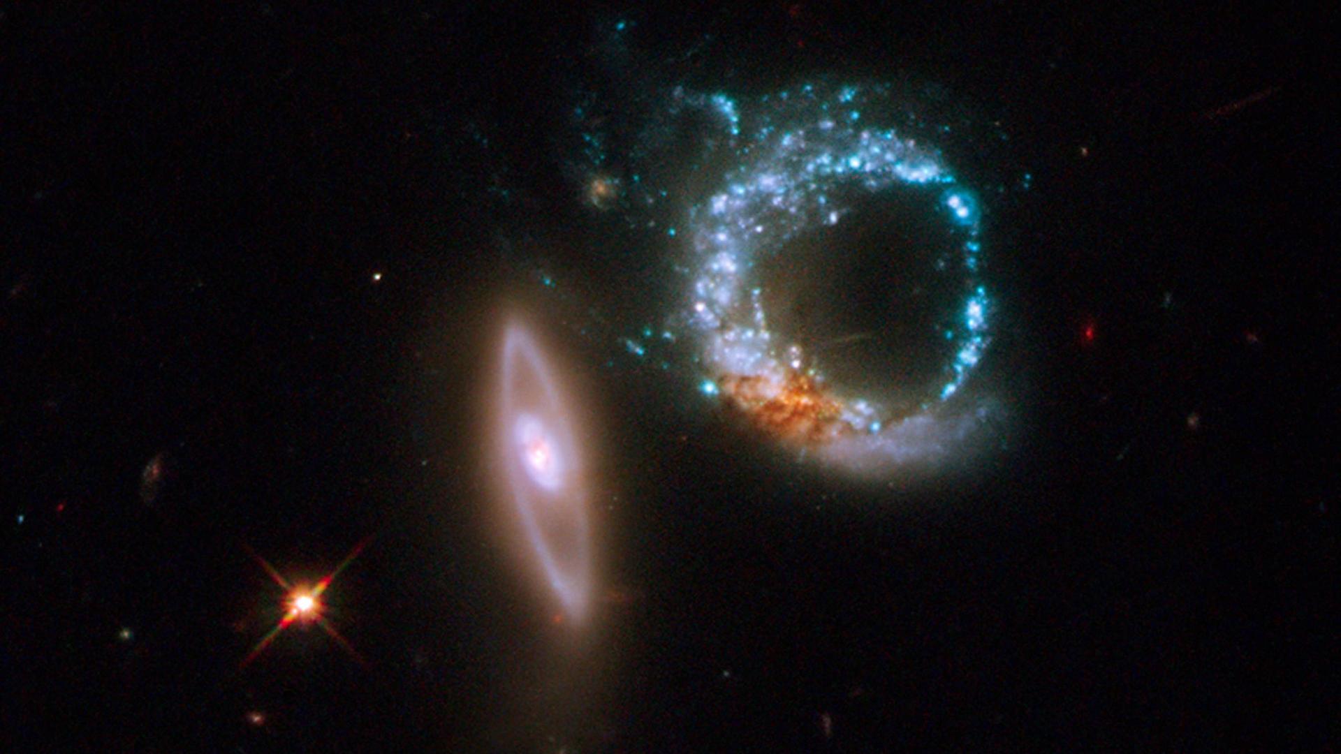 Neben zwei kreisförmigen Sternenwolken leuchtet ein einzelner Stern in der Tiefe des Weltalls besonders hell auf. Neben zwei kreisförmigen Sternenwolken leuchtet ein einzelner Stern in der Tiefe des Weltalls besonders hell auf.