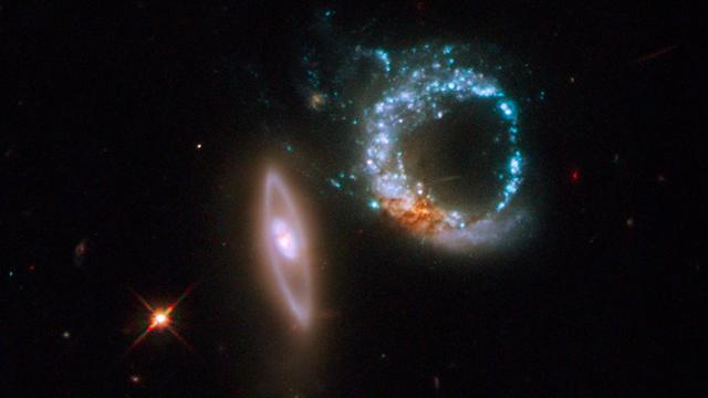 Neben zwei kreisförmigen Sternenwolken leuchtet ein einzelner Stern in der Tiefe des Weltalls besonders hell auf.