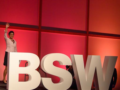 Sahra Wagenknecht steht auf der Bühne vor den Großbuchstaben BSW und winkt.