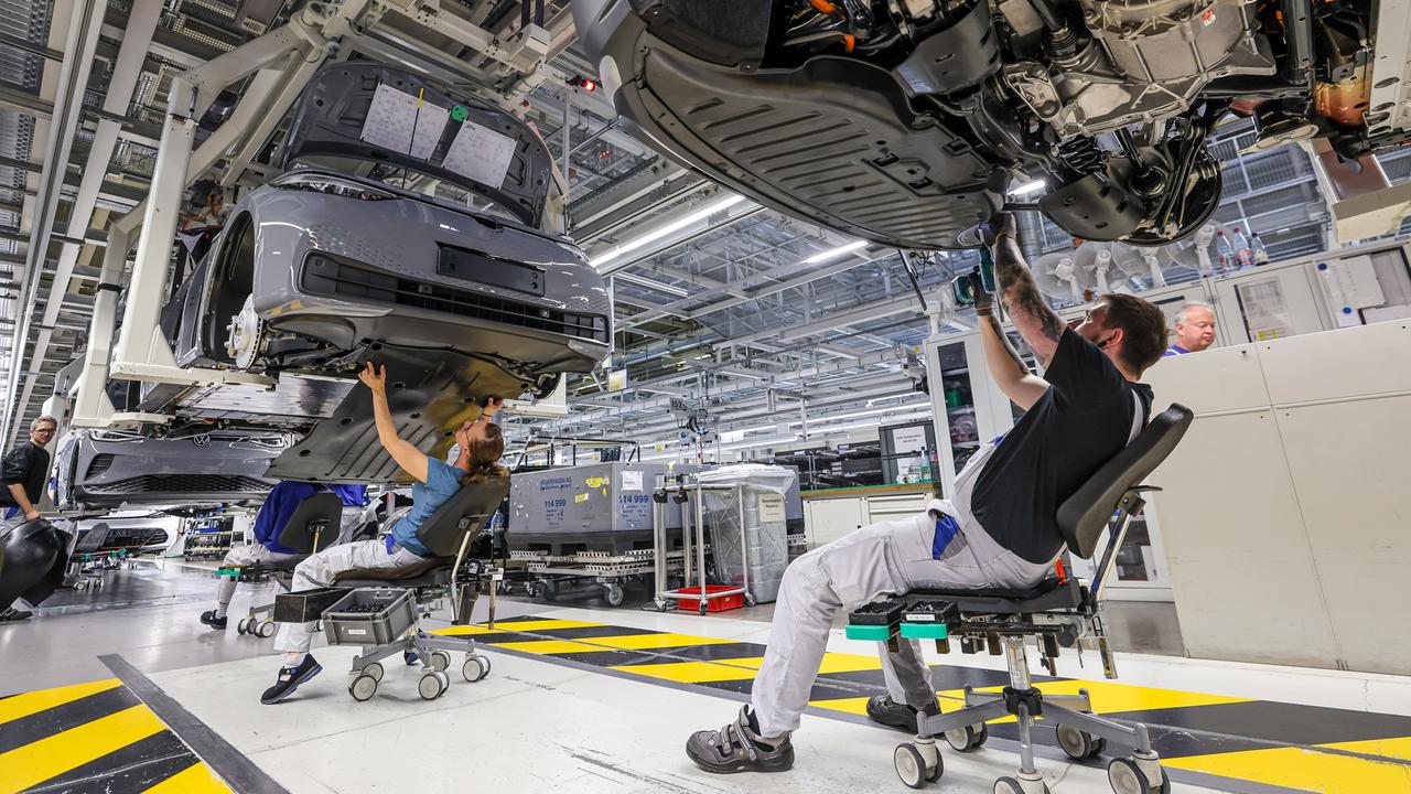 Mitarbeiter montieren den Unterbodenschutz an einem ID.4 im Werk von Volkswagen in Zwickau. 