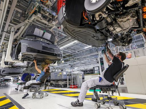 Mitarbeiter montieren den Unterbodenschutz an einem ID.4 im Werk von Volkswagen in Zwickau. 