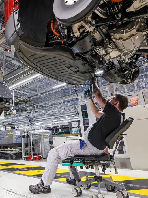 Mitarbeiter montieren den Unterbodenschutz an einem ID.4 im Werk von Volkswagen in Zwickau. 