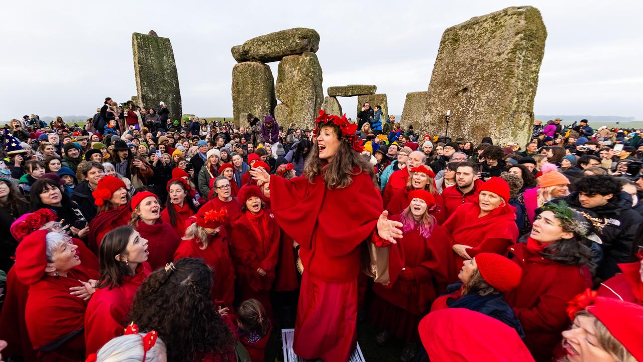 Menschen mit roten Kostümen feiern die Wintersonnenwende am Monument Stonehenge in England.