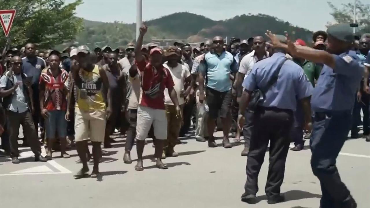 Papua-Neuguinea, Port Moresby: Dieses Videostandbild zeigt zwei Polizisten, die eine große Anzahl Menschen bei einem Protest zu kontrollieren.
