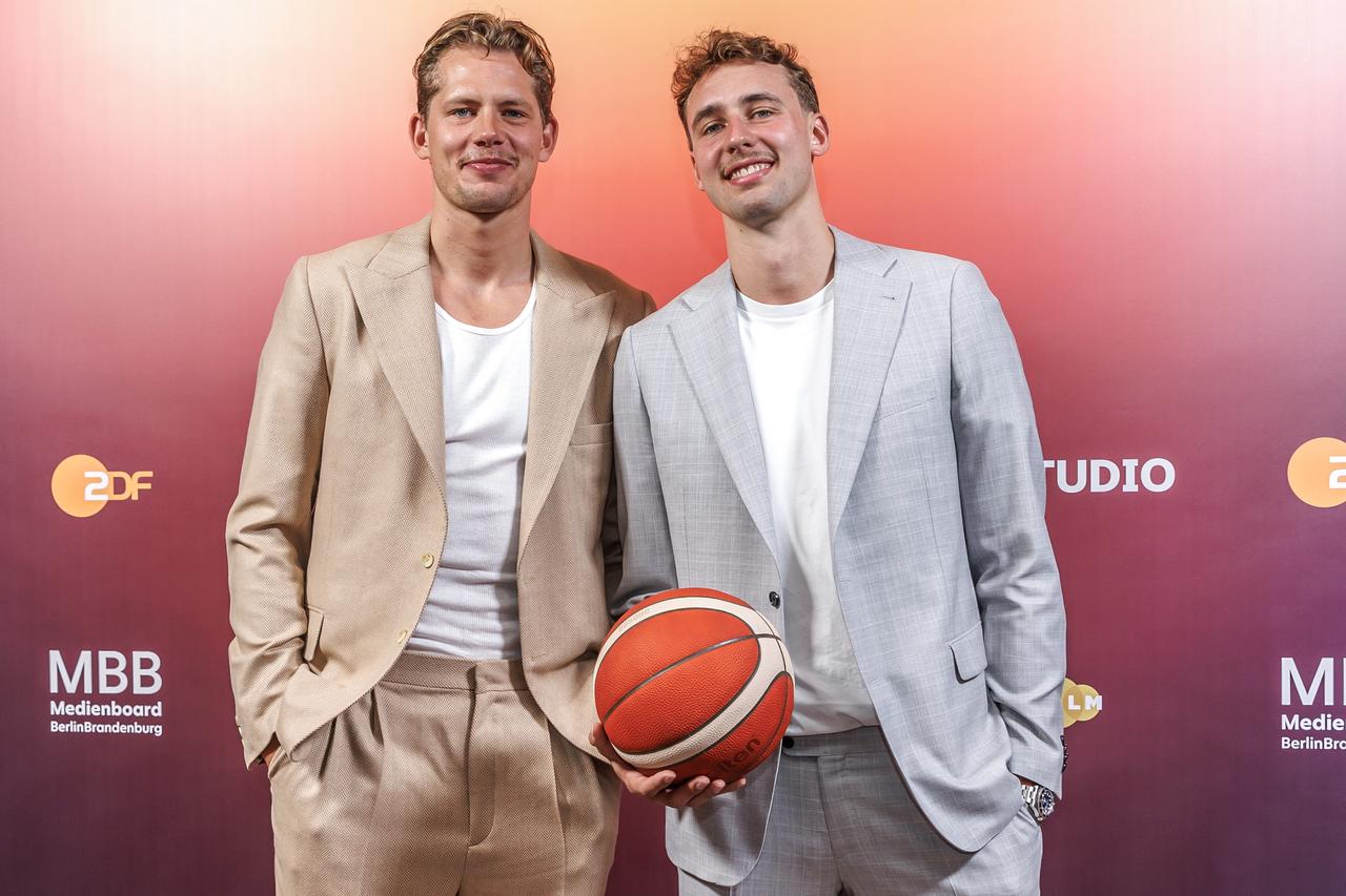 Die Basketballprofis und Brüder Moritz Wagner (l) und Franz Wagner stehen mit einem Basketball bei einem Fototermin vor der Preview zum Teil 1 der ZDF-Doku "THE WAGNER BROTHERS: Zwei Brüder, ein Traum" im Colosseum Filmtheater Berlin. 