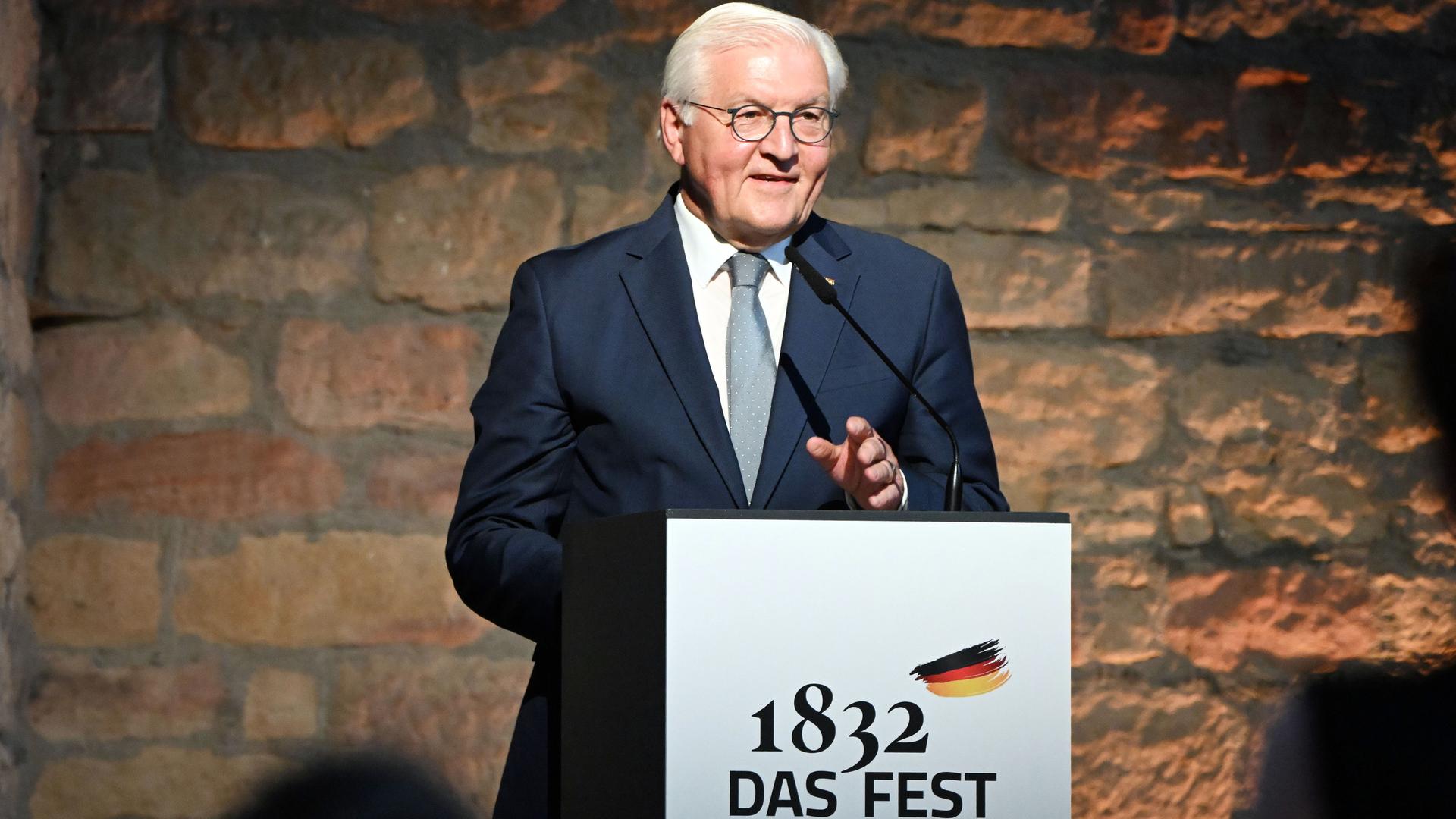 Bundespräsident Frank-Walter Steinmeier steht am Rednerpult im Hambacher Schloss vor einer Steinwand und spricht in das Mikrofon. Er träght einen dunklen Anzug. Bundespräsident Frank-Walter Steinmeier steht am Rednerpult im Hambacher Schloss vor einer Steinwand und spricht in das Mikrofon. Er träght einen dunklen Anzug.