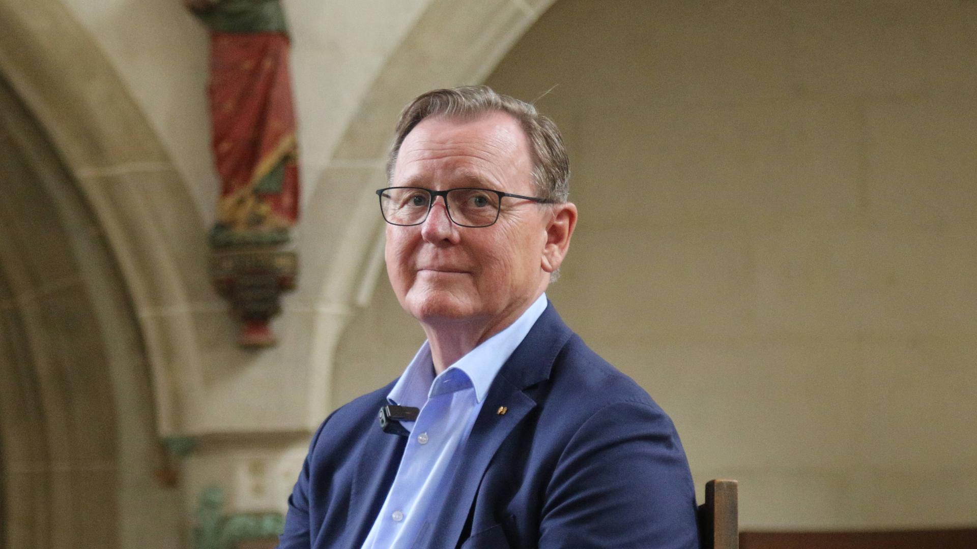 Ein Mann in blauem Jacket, der Budnestagsabgeordnete Bodo Ramelow (Die Linke) seitz auf einem Stuhl in einer Kirche