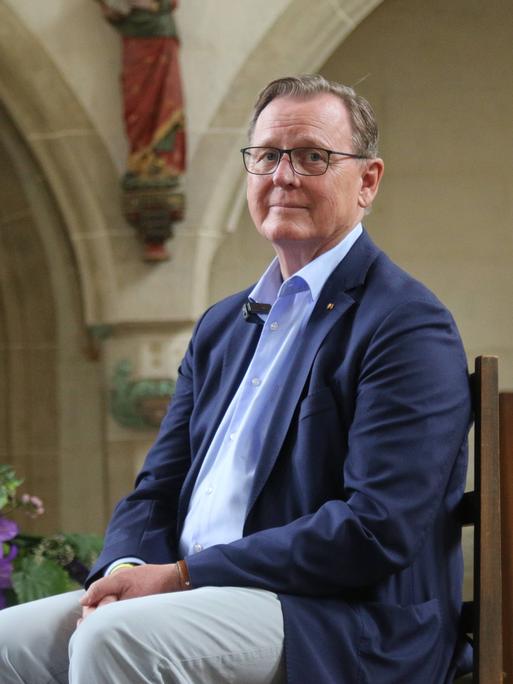 Ein Mann in blauem Jacket, der Budnestagsabgeordnete Bodo Ramelow (Die Linke) seitz auf einem Stuhl in einer Kirche