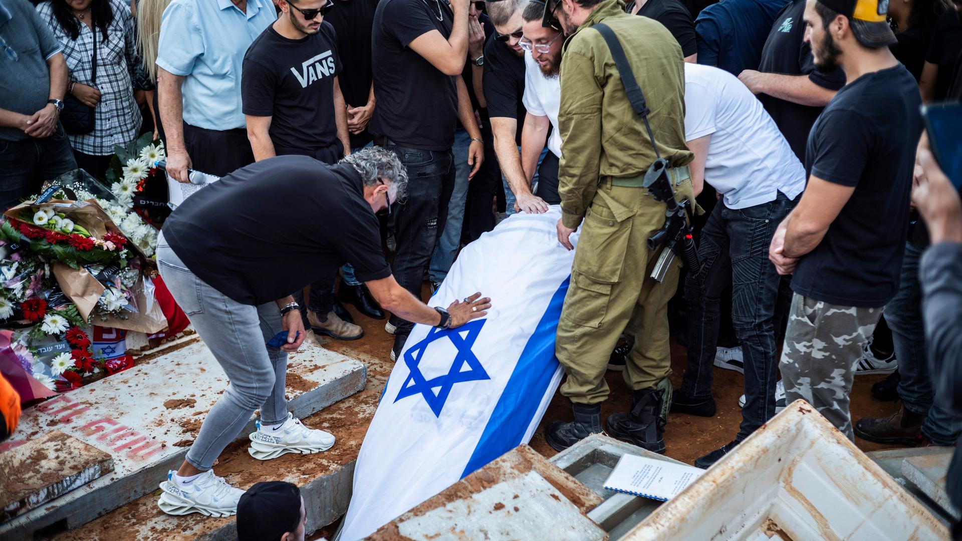 Ein Leichnam, der in eine israelische Flagge eingewickelt ist, wird in ein Grab gelegt.