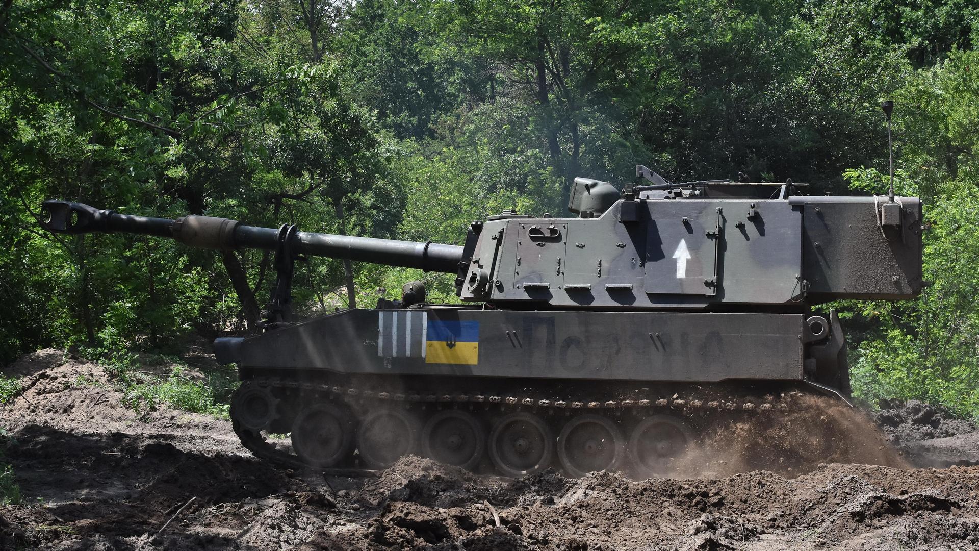 Eine 155-mm-Panzerhaubitze mit der aufgezeichneten ukrainischen Flagge im Wald.