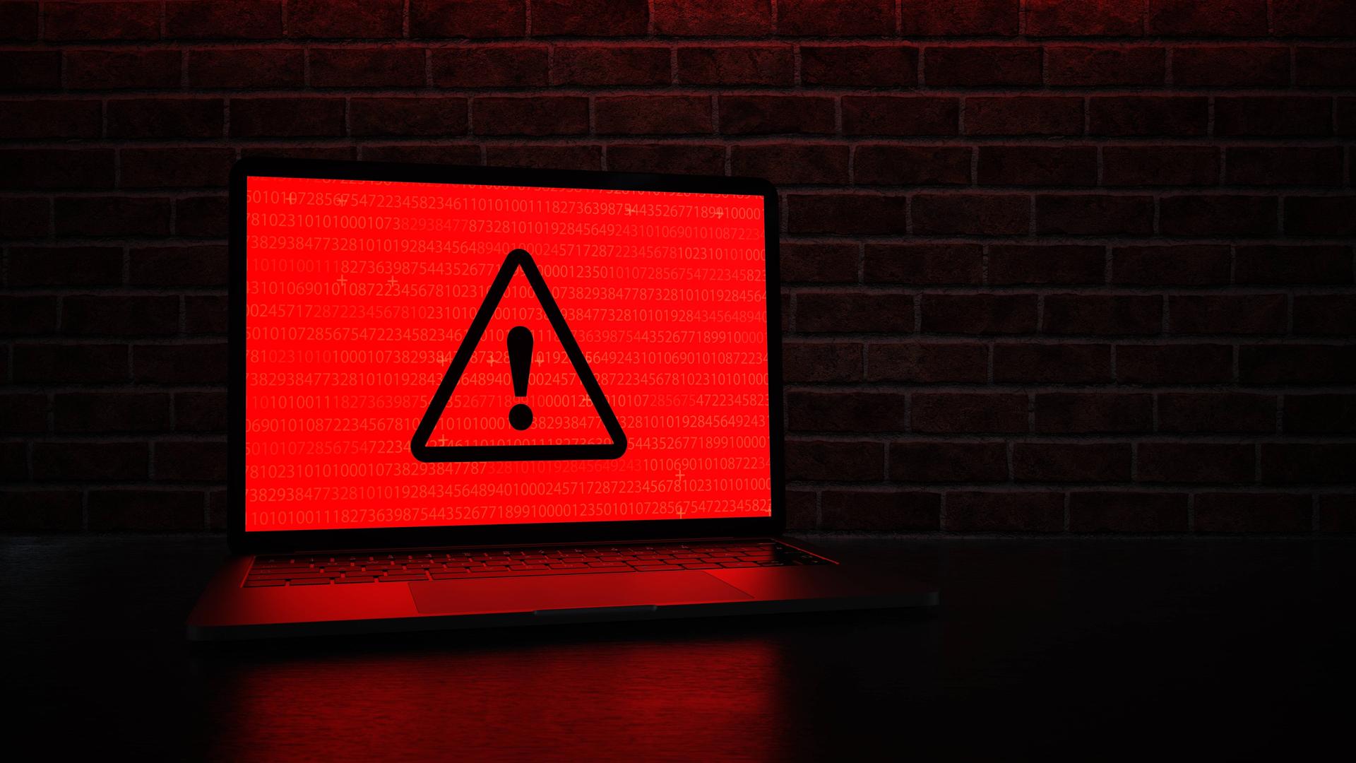 Ein Laptop mit einem roten Warnsymbol auf dem Bildschirm. Ein Laptop mit einem roten Warnsymbol auf dem Bildschirm.