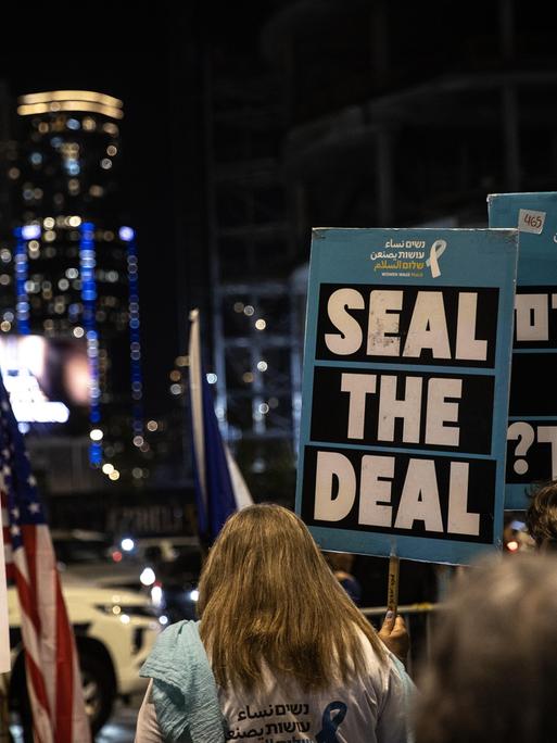 Angehörige der Hamas-Geiseln auf einer Straße in Tel Aviv . Auf einem Schild steht geschrieben "Seal the Deal". Auch zwei US-Flaggen sind zu sehen. Aufnahmedatum: 14. Januar 2025.
