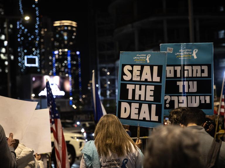 Angehörige der Hamas-Geiseln auf einer Straße in Tel Aviv . Auf einem Schild steht geschrieben "Seal the Deal". Auch zwei US-Flaggen sind zu sehen. Aufnahmedatum: 14. Januar 2025.
