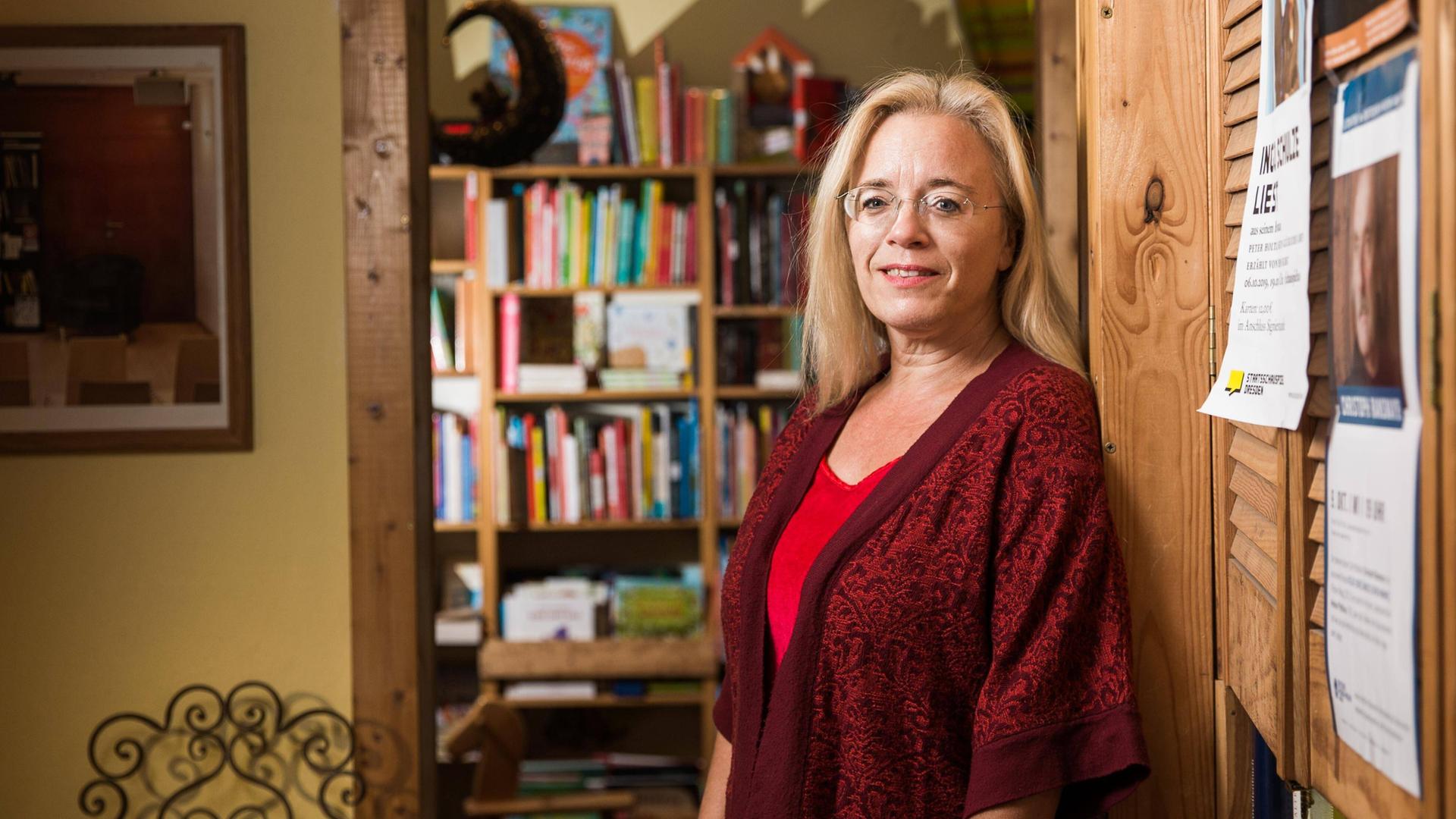 Die Dresdner Buchhändlerin Susanne Dagen im roten Kleid mit Jacke. Sie steht vor einer Bücherwand. 