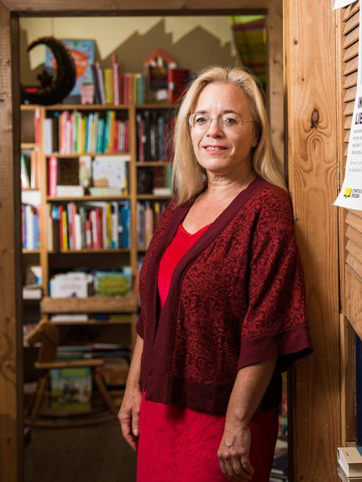 Die Dresdner Buchhändlerin Susanne Dagen im roten Kleid mit Jacke. Sie steht vor einer Bücherwand. 