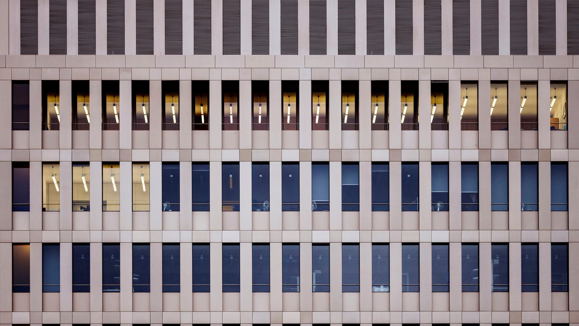 Blick von außen auf die hellbraune Fassade des Bundesnachrichtendienstes in Berlin. Mehrere Fensterreihen, in wenigen Fenstern brennt Licht. Es ist tags.
