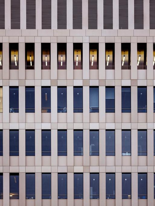 Blick von außen auf die hellbraune Fassade des Bundesnachrichtendienstes in Berlin. Mehrere Fensterreihen, in wenigen Fenstern brennt Licht. Es ist tags.