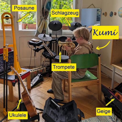Ein blonder Junge sitzt in seinem Zimmer auf einem Stuhl und spielt Trompete, um ihn herum sind einige andere Instrumente zu sehen, ein Schlagzeug, eine Ukulele, eine Posaune und eine Geige