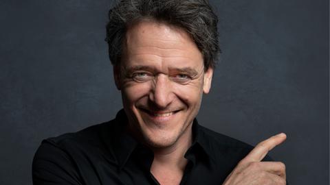 Der österreichische Musikkabarettist Christof Spörk lacht in die Kamera