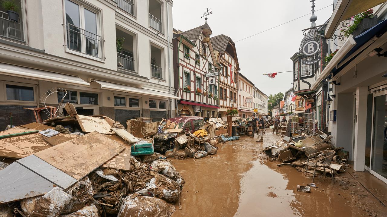 Anwohner und Ladeninhaber versuchen, ihre Häuser vom Schlamm zu befreien und unbrauchbares Mobiliar nach draußen zu bringen. 