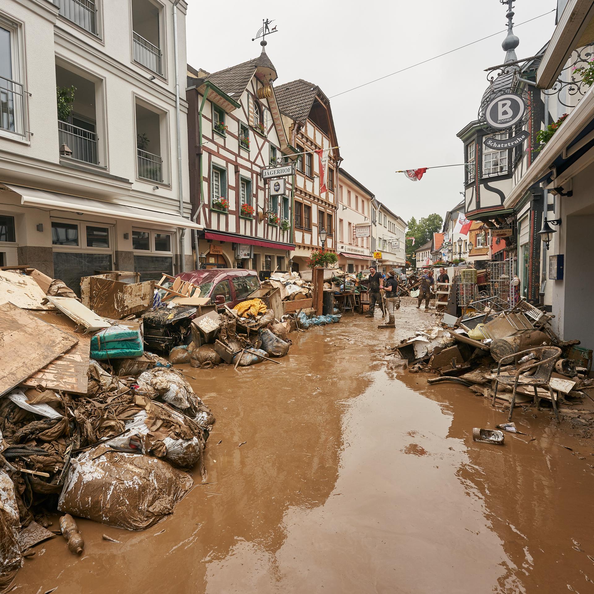 Anwohner und Ladeninhaber versuchen, ihre Häuser vom Schlamm zu befreien und unbrauchbares Mobiliar nach draußen zu bringen. 