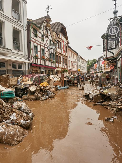 Anwohner und Ladeninhaber versuchen, ihre Häuser vom Schlamm zu befreien und unbrauchbares Mobiliar nach draußen zu bringen. 