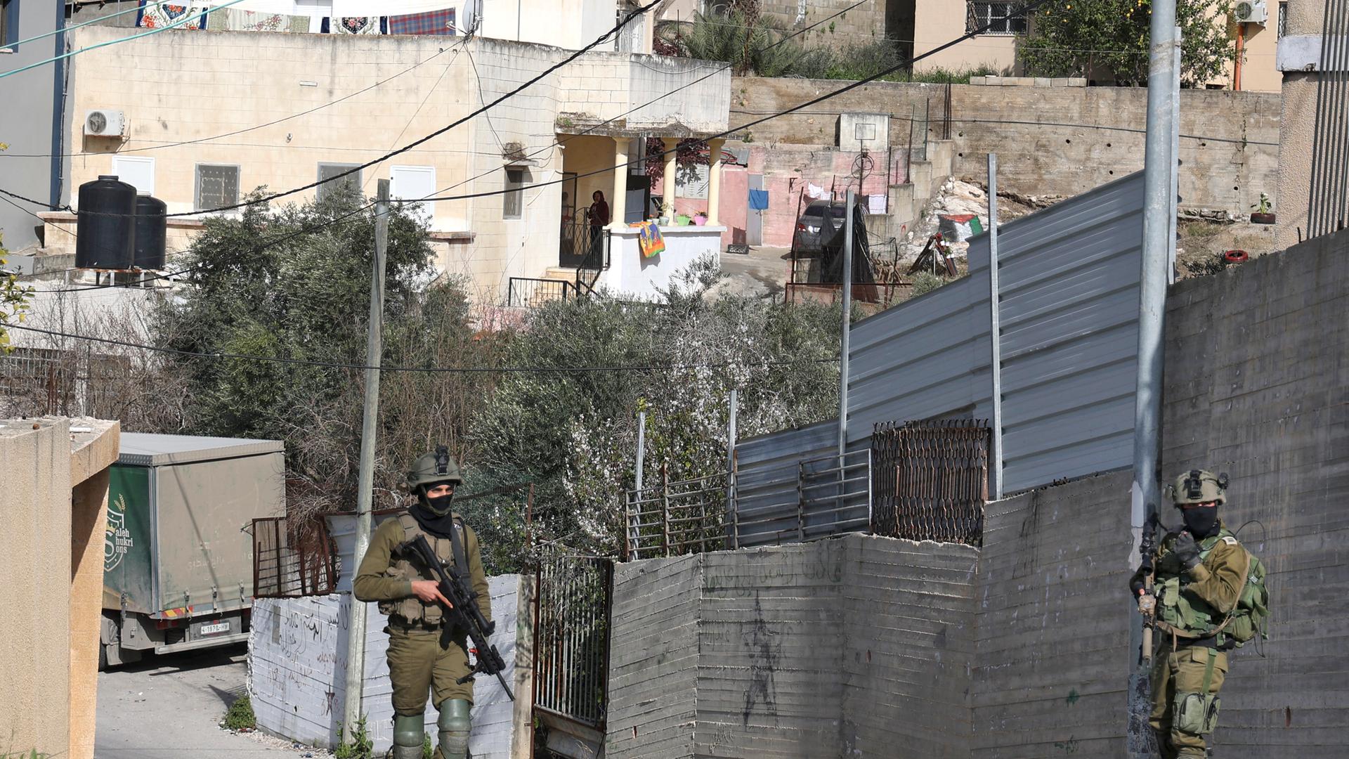 Zwei bewaffnete israelische Soldaten laufen durch einen Ort in der Nähe von Dschenin im besetzten Westjordanland.