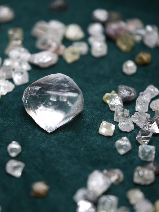 Diamanten in verschiedenen Größen liegen auf einem dunklen Untergrund.