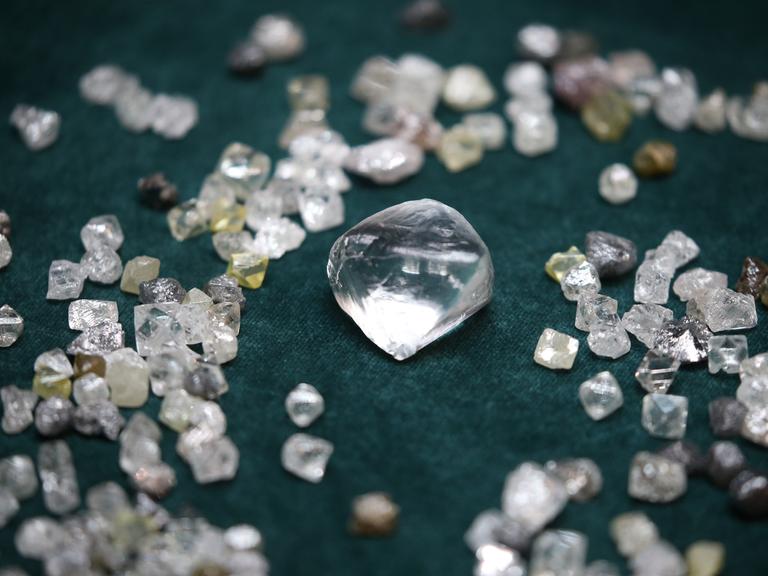 Diamanten in verschiedenen Größen liegen auf einem dunklen Untergrund.