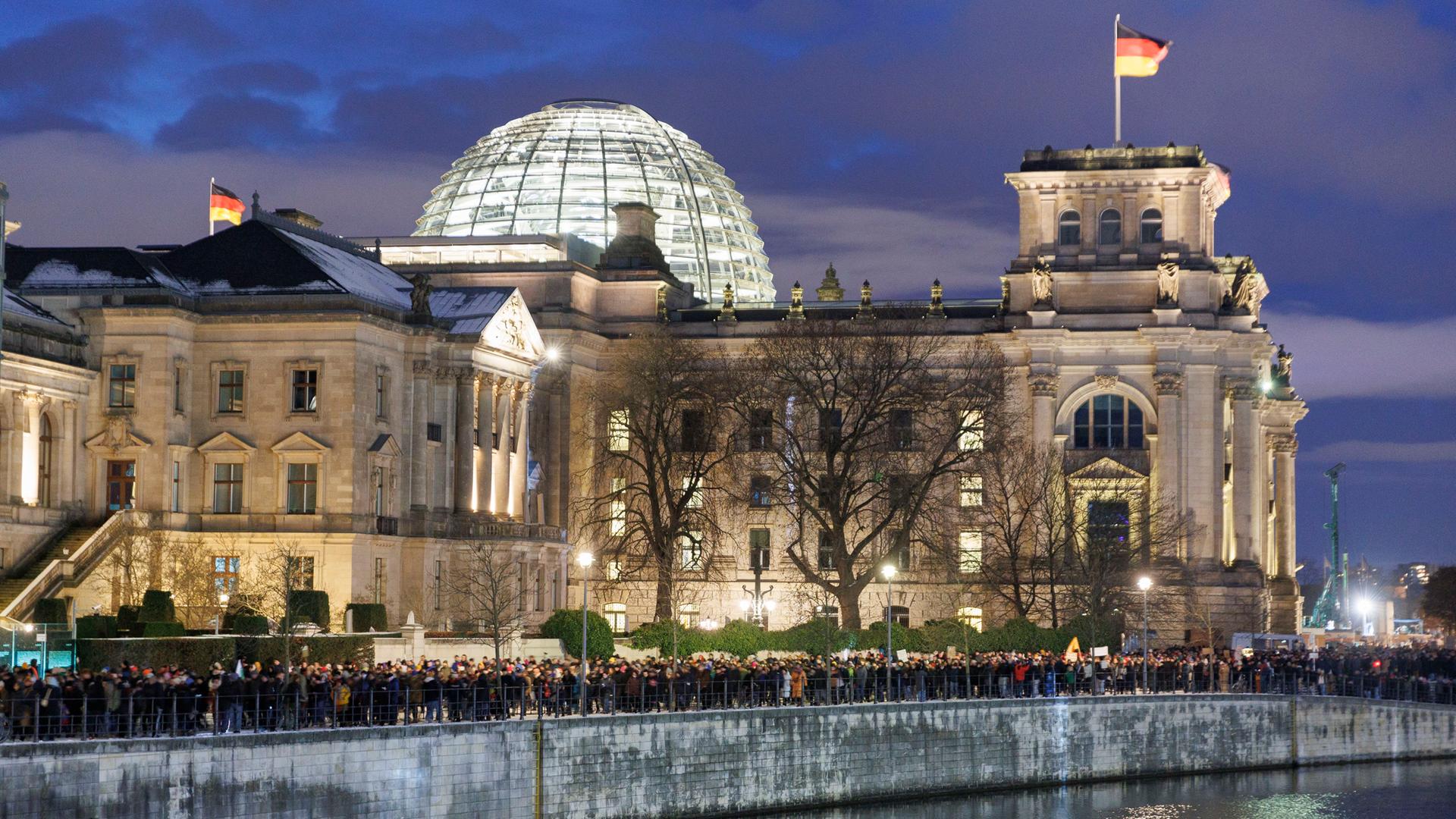 Menschen laufen beim Verlassen einer Protestveranstaltung unter dem Motto "Demokratie verteidigen" am Berliner Reichstagsgebäude vorbei.
