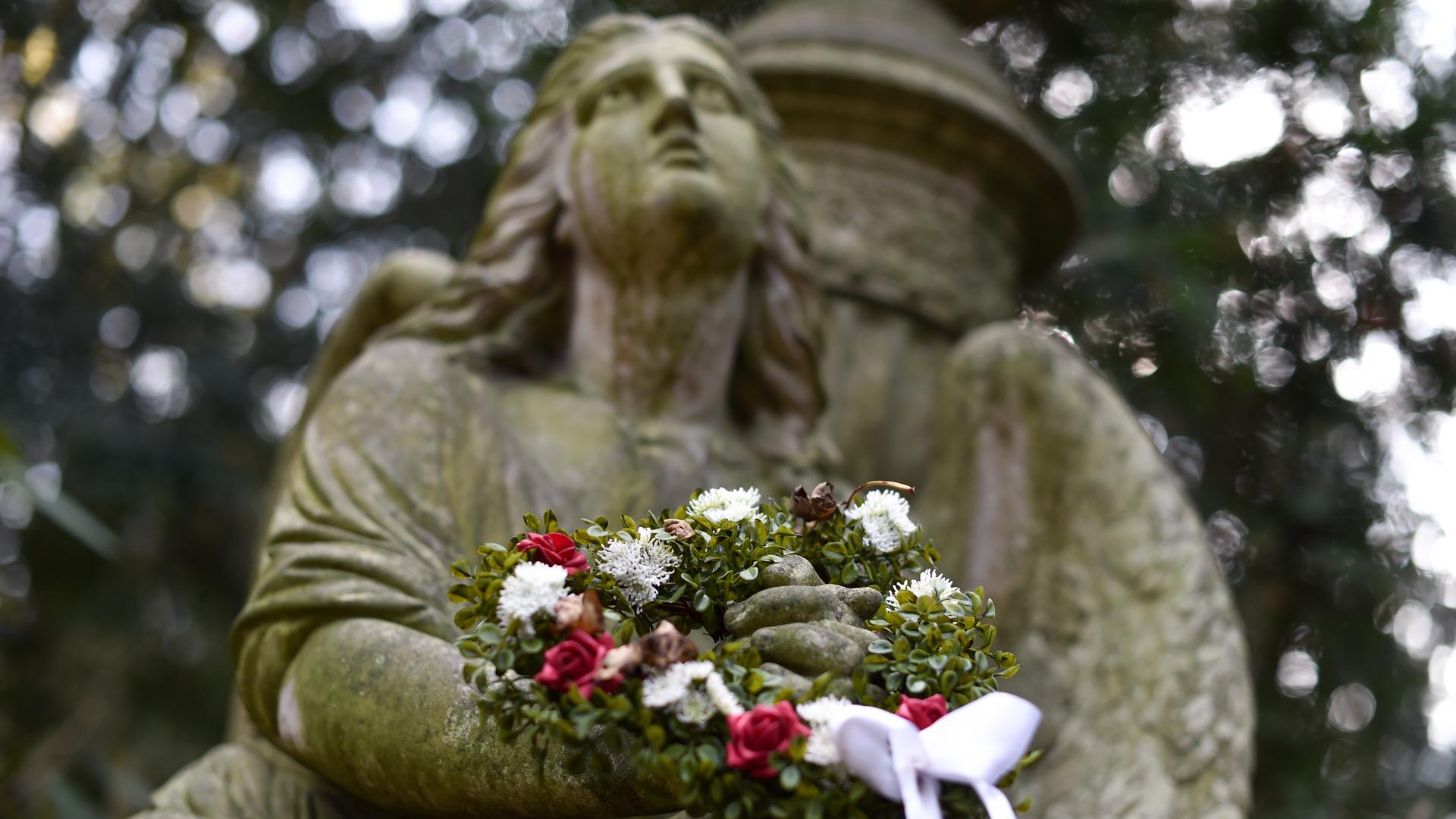 Ein Trauerengel mit Blumenkranz auf dem Hauptfriedhof in Frankfurt am Main.
