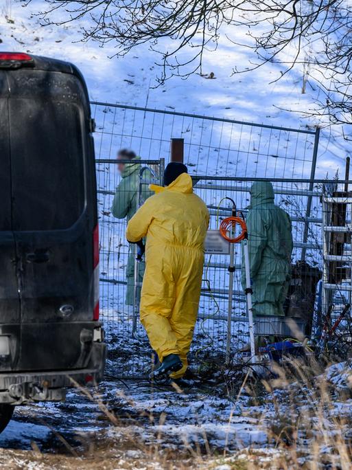 Personen in Schutzkleidung gehen über eine verschneite Weide. Feuerwehr und Polizei das Gelände weiträumig abgesperrt haben.