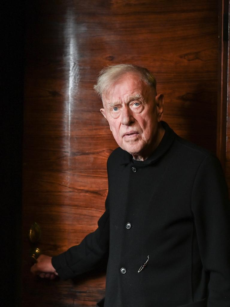 Claus Peymann steht vor einer Holzvertäfelung und blick ernst in die Kamera