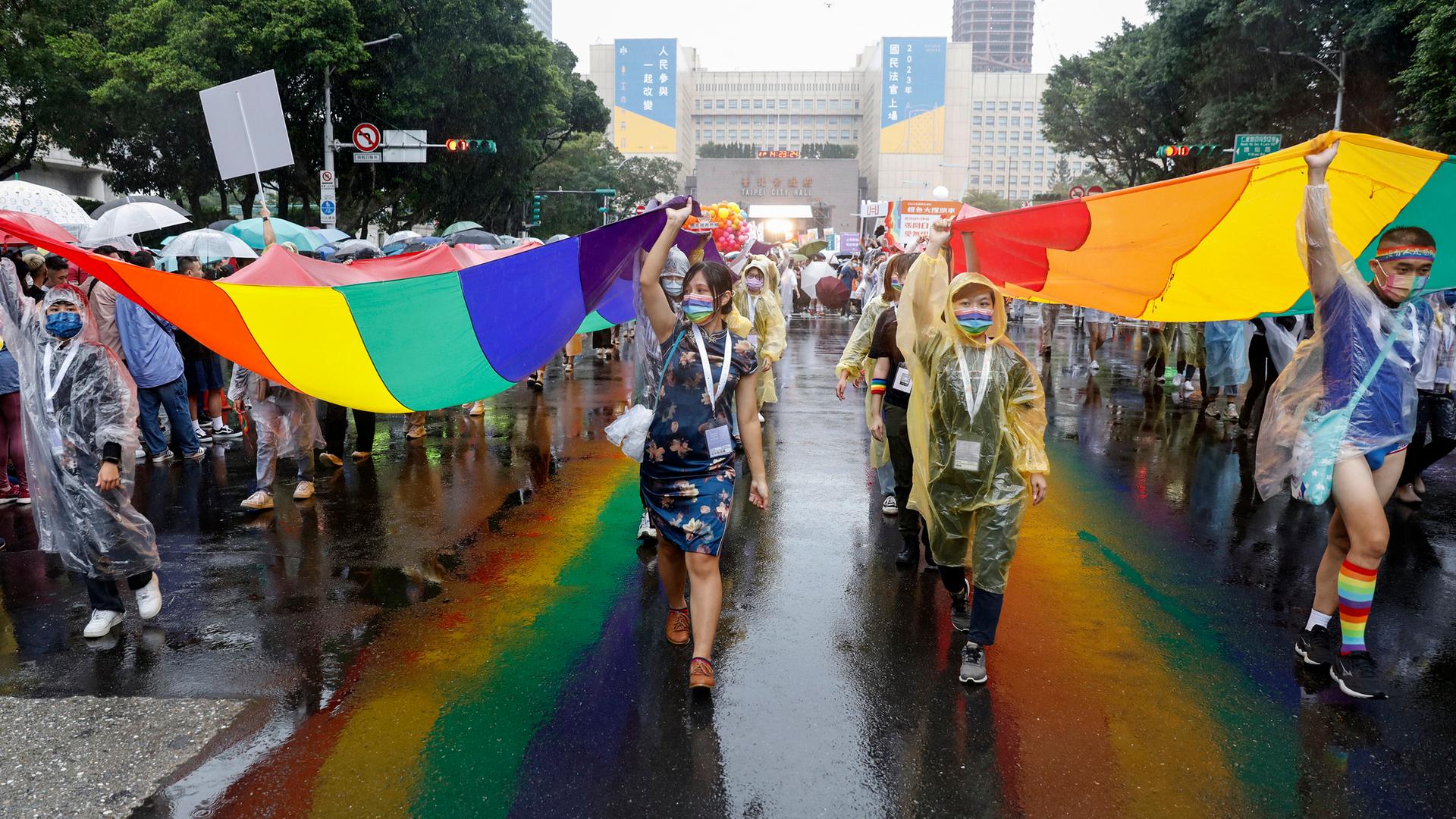 Teilnehmer der LGBT-Parade in Taipeh auf der Straße mit Regenbogenfahne.