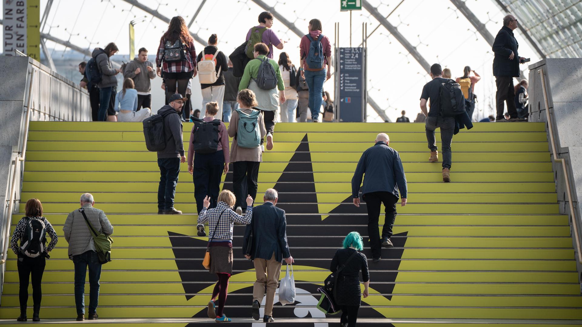 Blick auf die Leipziger Buchmesse am ersten Messetag: Zahlreiche Personen gehen eine Treppe nach oben. Blick auf die Leipziger Buchmesse am ersten Messetag: Zahlreiche Personen gehen eine Treppe nach oben.